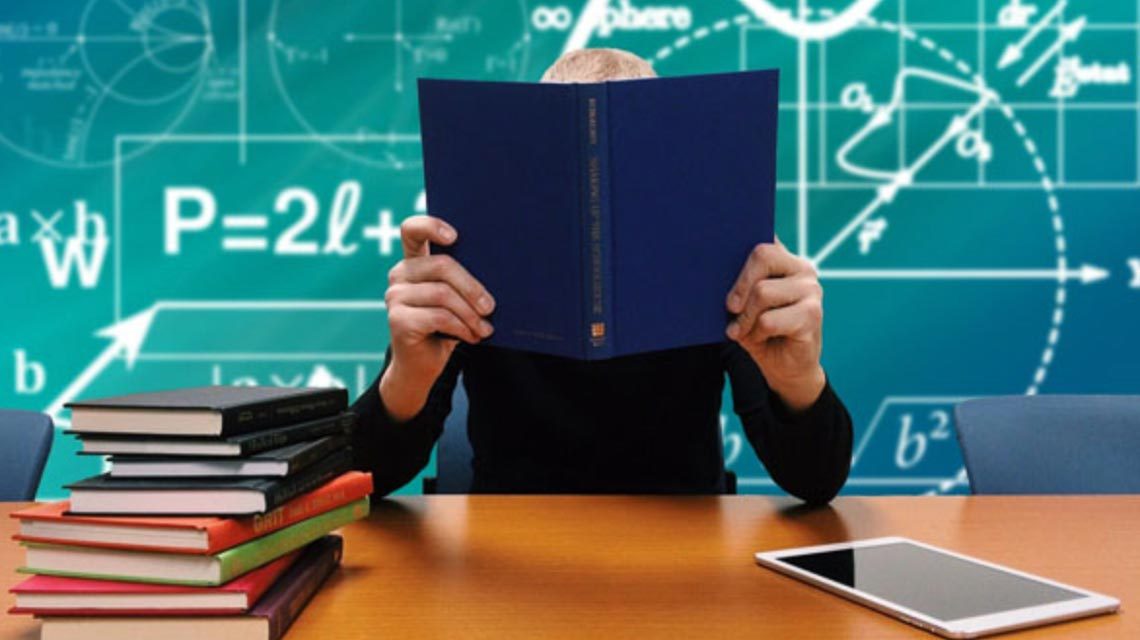 Schüler steckt sein Gesicht in Bücher im Klassenzimmer. Pisa Studie