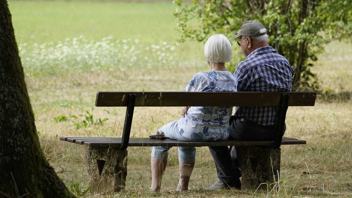 Zwei Senioren sitzen auf der Parkbank und blicken in die Ferne