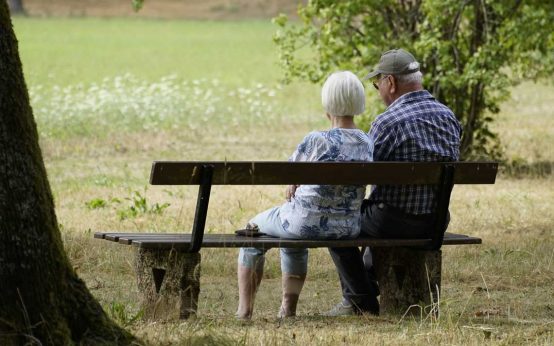 Zwei Senioren sitzen auf der Parkbank und blicken in die Ferne