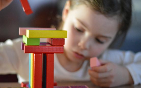 Kleines Kind spielt mit Bauklötzen. Kinderbetreuung.