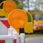 Baustellenabsperrung im Vordergrund, dahinter Baustellenfahrzeige in der Unschärfe.